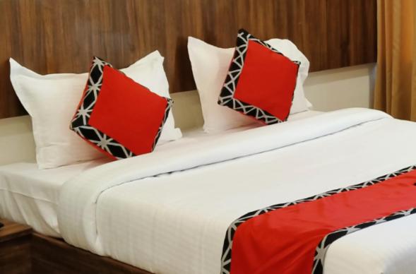 Una cama con almohadas rojas y blancas. en EMPIRE INN HOTEL, en Chennai