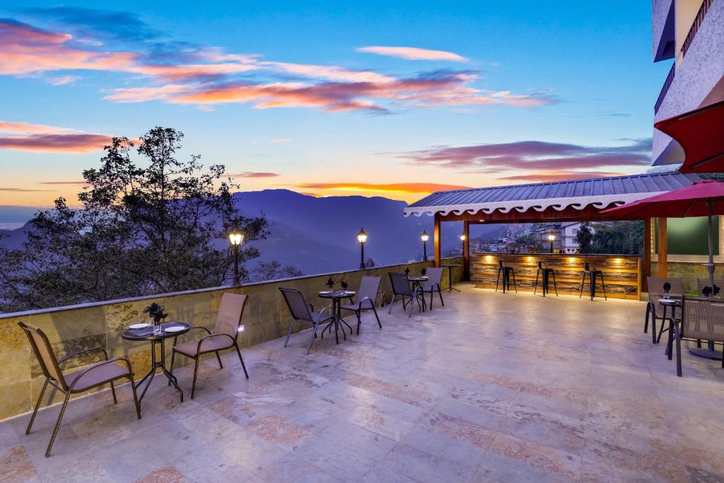 patio con mesas y sillas y puesta de sol en Mount Himalayan Hotel en Gangtok