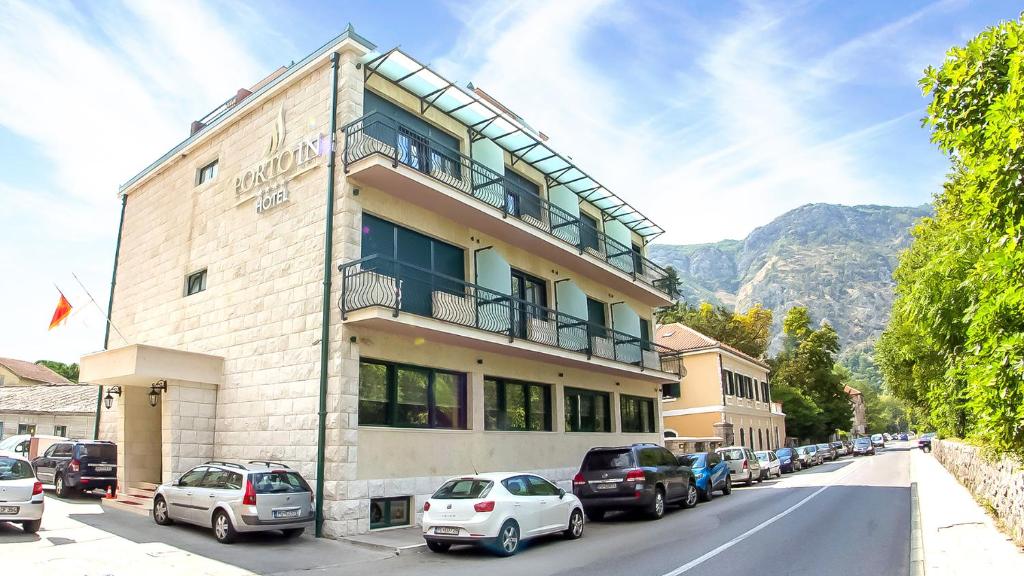 a building with cars parked on the side of a street at Hotel Porto In in Kotor