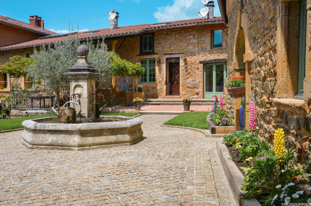 a stone courtyard with a fountain in front of a house at Studio et colocation - Gîte Les 7 fontaines in Chevinay