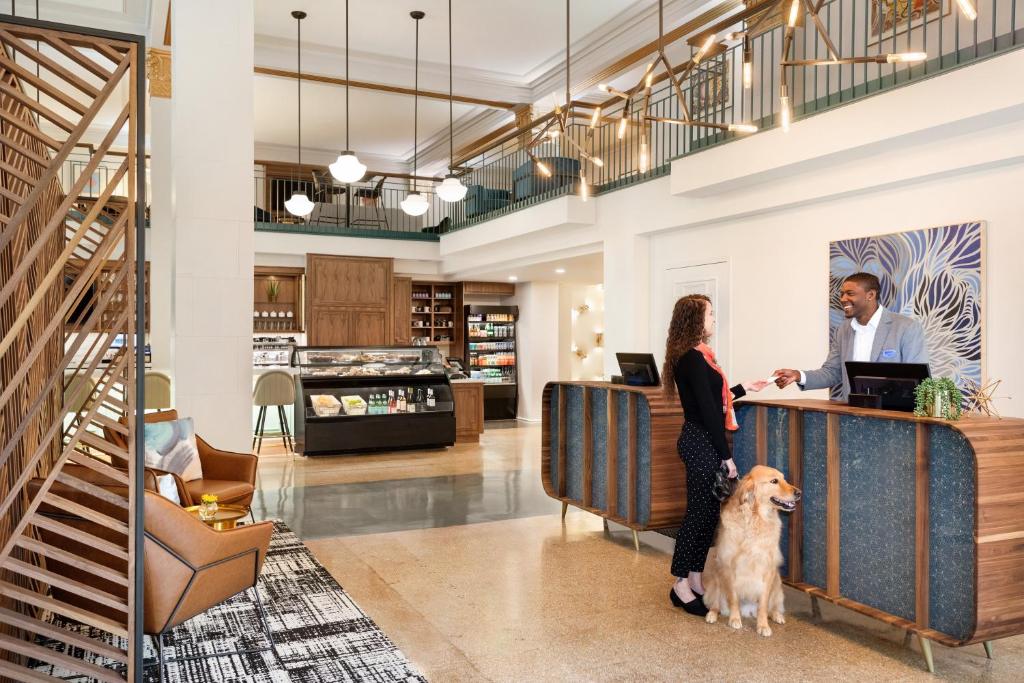 un homme et une femme debout au comptoir avec un chien dans l'établissement Hotel Indigo - Winston-Salem Downtown, an IHG Hotel, à Winston-Salem