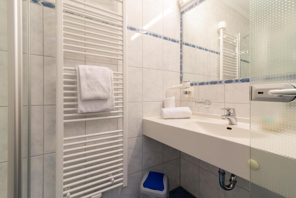 a white bathroom with a sink and a mirror at Hotel & Gasthof Richard Held in Regensburg