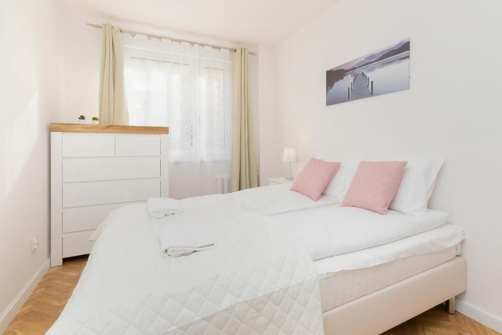 - une chambre avec un lit blanc et des oreillers roses dans l'établissement Apartment Nevada Gdańsk Przymorze by Renters, à Gdańsk