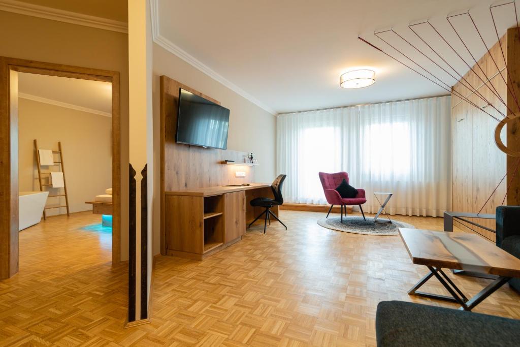 a living room with a table and chairs and a desk at Hotel & Gasthof Richard Held in Regensburg