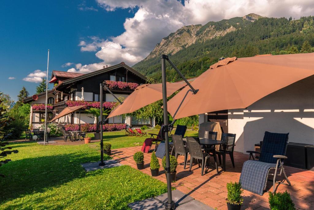eine Terrasse mit einem Tisch, Stühlen und einem Sonnenschirm in der Unterkunft Gästehaus Birkenhof in Oberstdorf