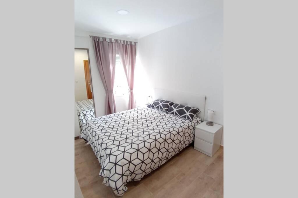 a white bedroom with a bed and a window at Apartamentos en Alameda junto al Corte Inglés in Cartagena