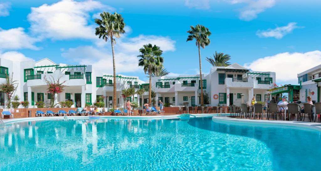 une piscine dans un complexe hôtelier avec des palmiers dans l'établissement Apartamentos Luz Y Mar, à Puerto del Carmen