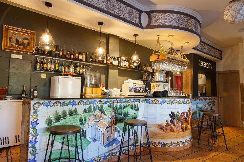 a bar with stools and a mural on the wall at La Orza de Angel in Chiva
