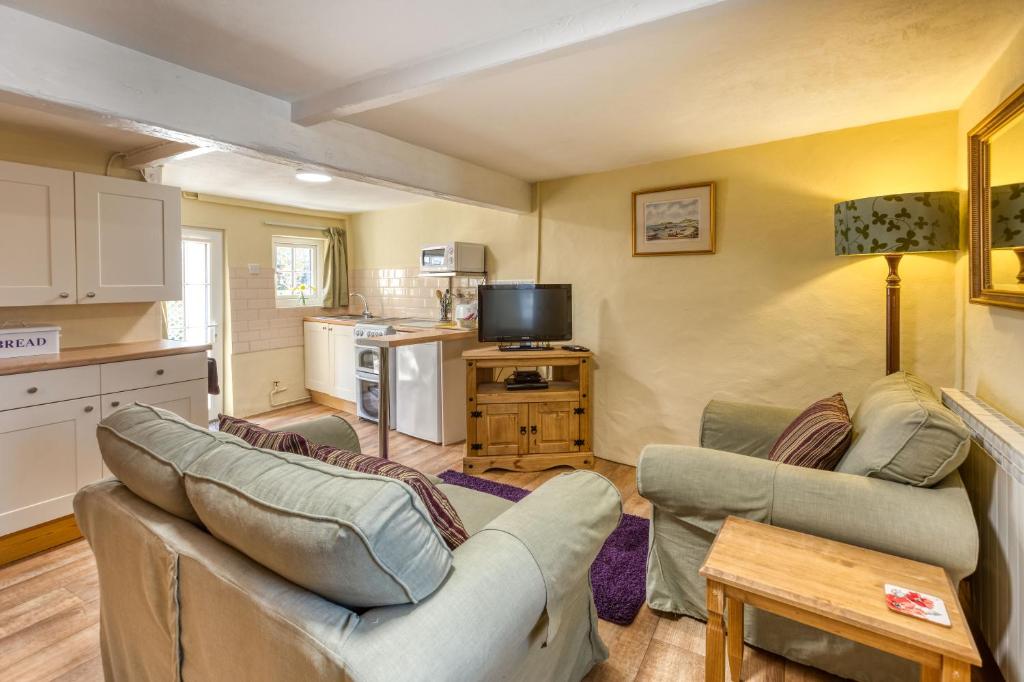 a living room with two couches and a kitchen at La Bellieuse Cottages in St Martin Guernsey