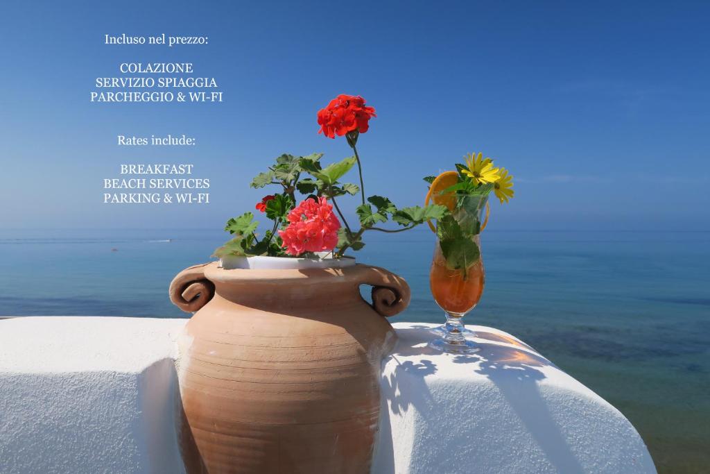 a vase with flowers in it next to a glass at Hotel Aurora in Sperlonga