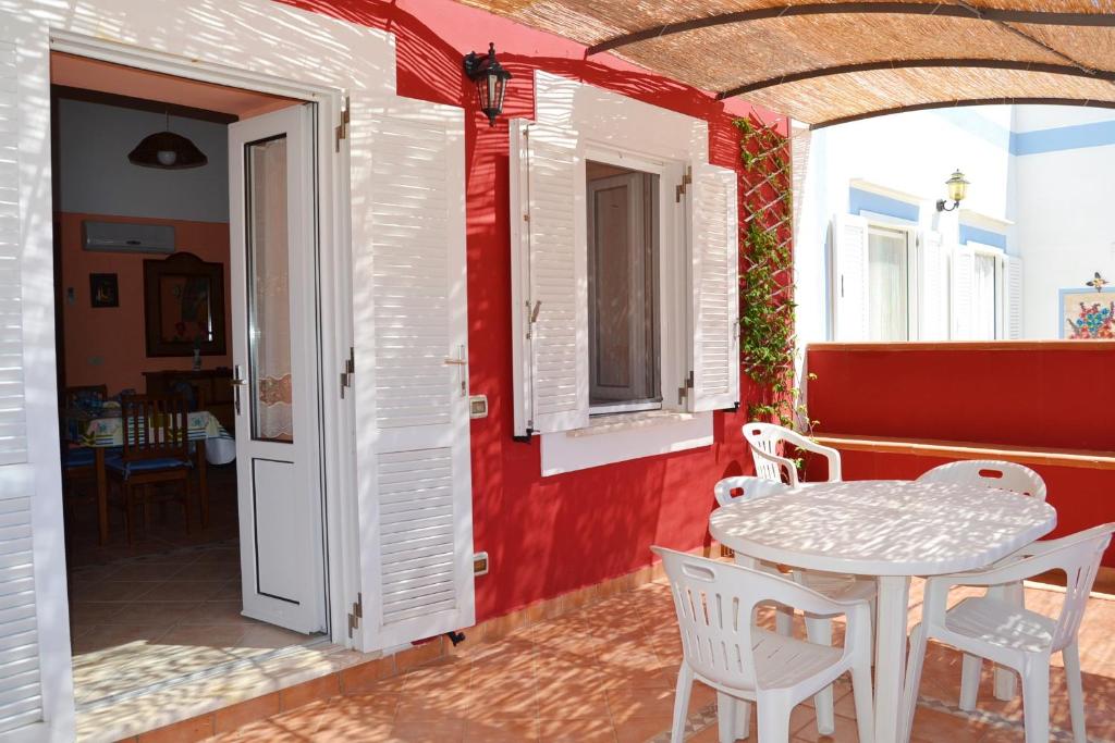 Zimmer mit einem Tisch, Stühlen und einer roten Wand in der Unterkunft Maridea - Fragolino in Ponza