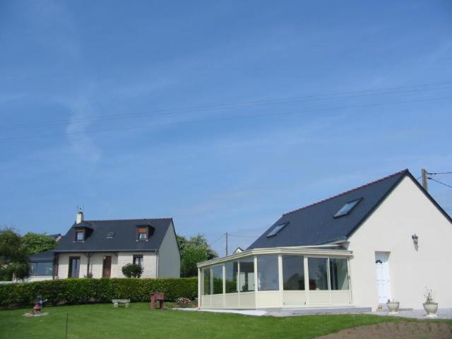 une grande maison blanche avec un toit solaire dans l'établissement CHAMBRES D'HÔTES chez réjane, à Crasville