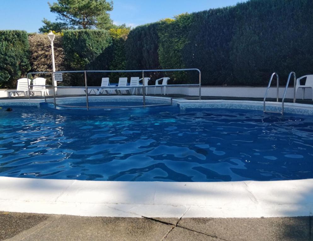 uma piscina com água azul e cadeiras brancas em Springside Chalet20 em Tywyn