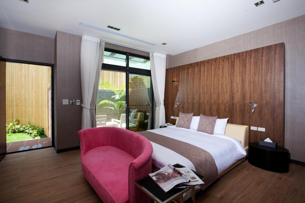 a bedroom with a large bed and a pink chair at Skyline B&B in Yuanshan