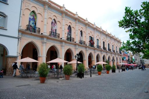 a large building with tables and chairs and umbrellas at La San Francisco III in Salta