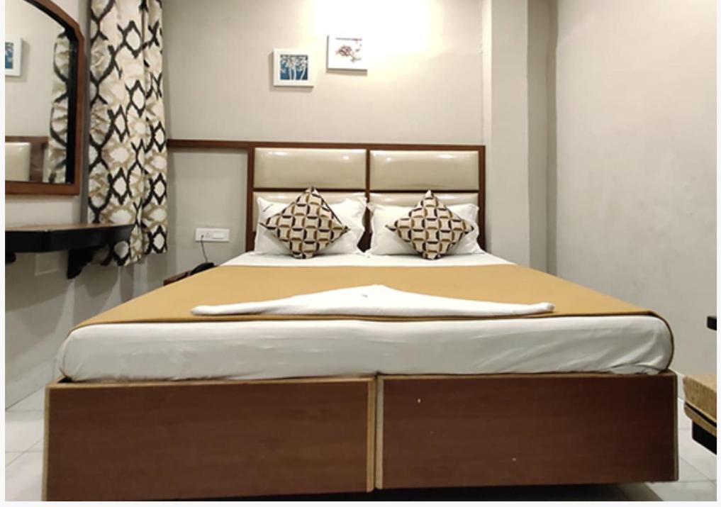 a bedroom with a large bed with a wooden headboard at SAROVAR INN in Chennai