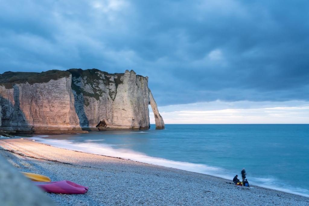 un grupo de personas sentadas en una playa junto al océano en VVF Normandie Veules-les-Roses, en Veules-les-Roses