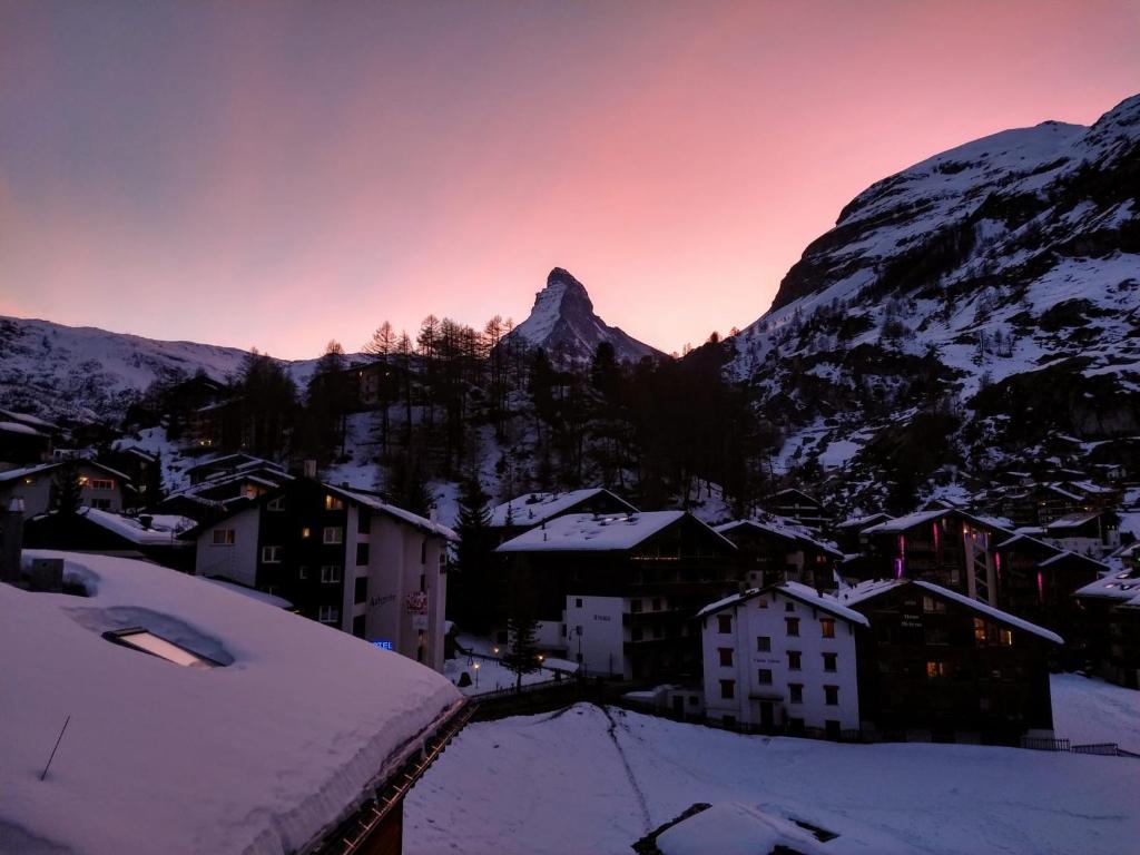 a village covered in snow with a mountain in the background at Chalet-style Apartment with Matterhorn View in Zermatt