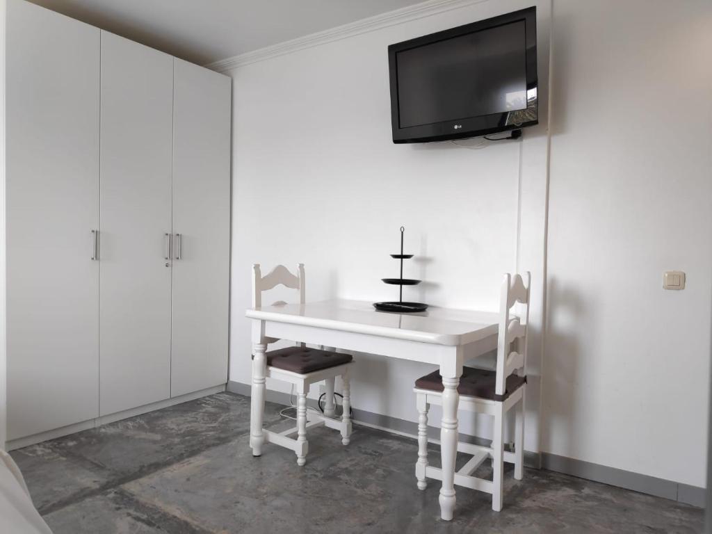 a white table with two chairs and a tv on a wall at Estudio Naos in Arrecife