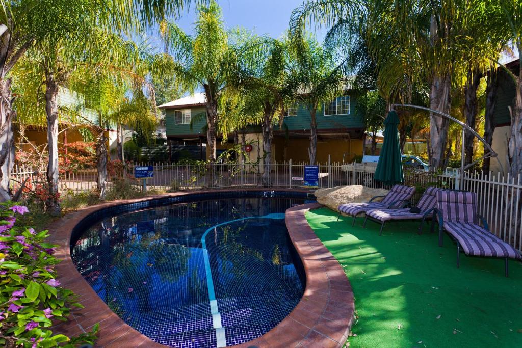 einen Pool mit zwei Liegestühlen und ein Haus in der Unterkunft Alice On Todd Apartments in Alice Springs