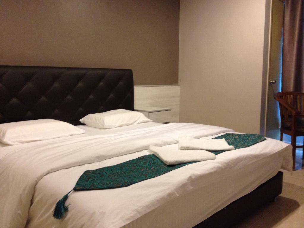 Una cama con toallas blancas y un vestido verde. en AERO Star Hotel, en Seremban