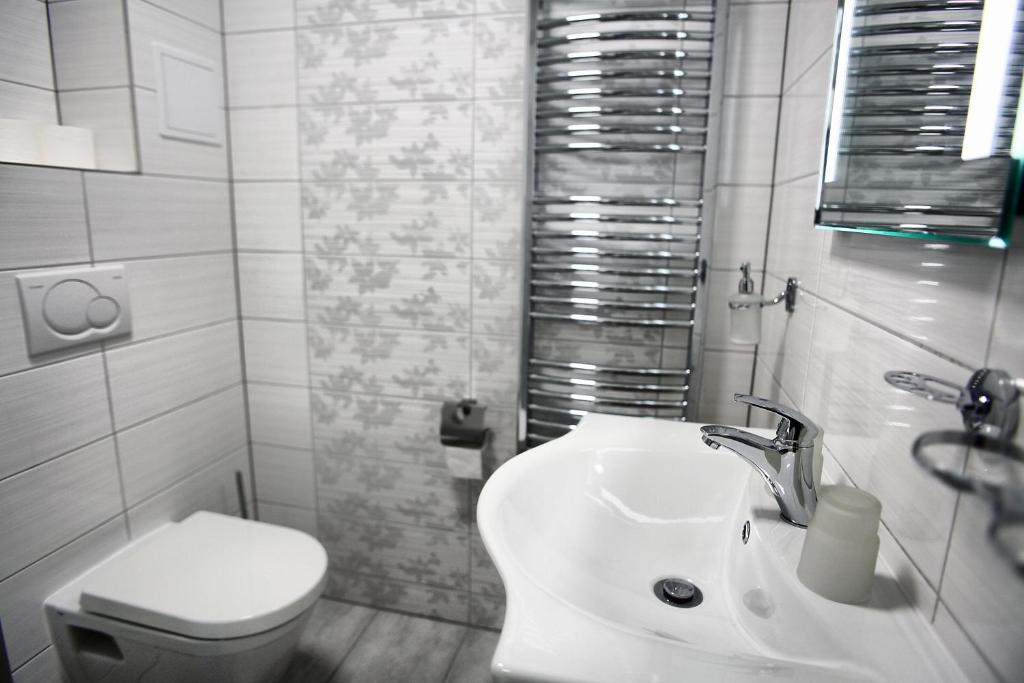 a white bathroom with a toilet and a sink at Hotel Kotva in Hřensko