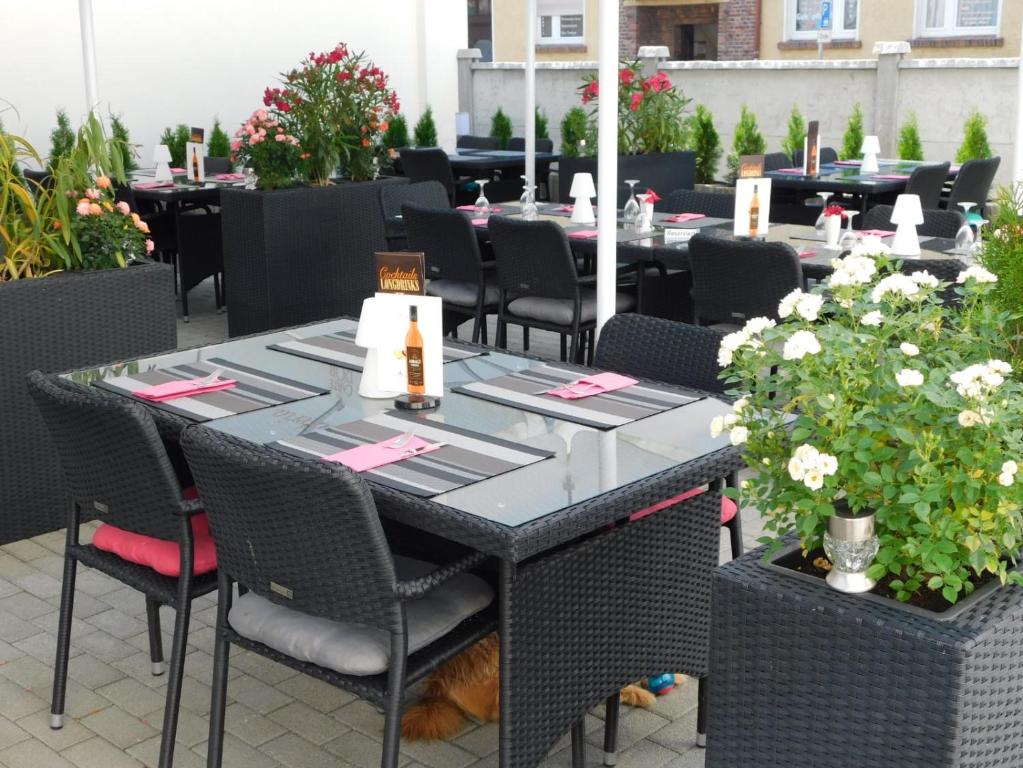 un comedor con mesas, sillas y flores en Hotel Anhalt en Köthen