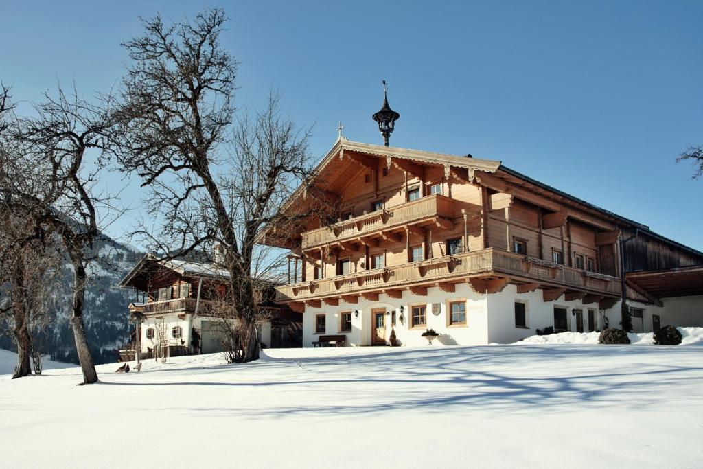 a large wooden building with snow on the ground at Apartment Wachinghof in Reith bei Kitzbühel
