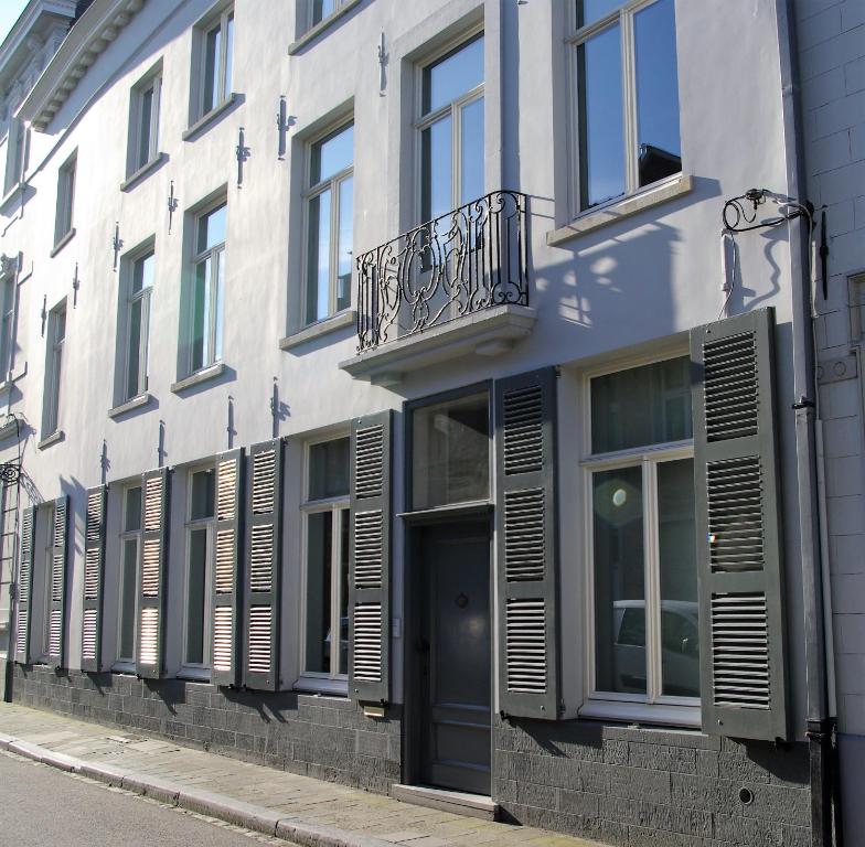 - un bâtiment blanc avec des fenêtres à volets et une porte dans l'établissement B&B Huyze Weyne, à Bruges