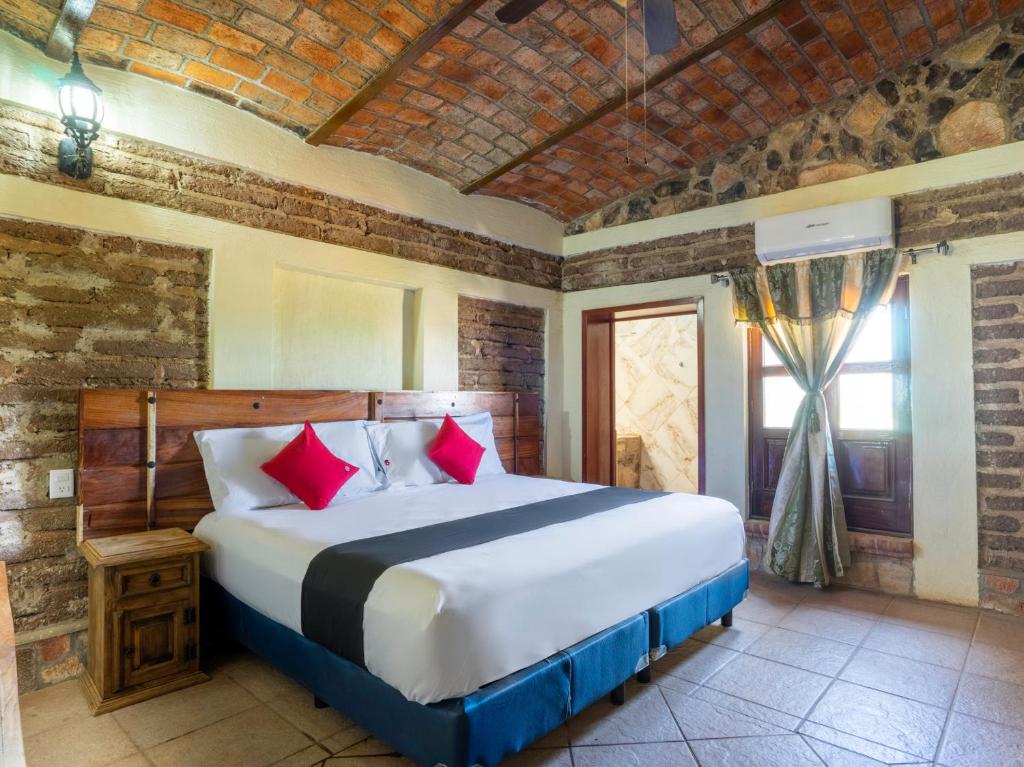 Capital O Hotel Posada Terraza, Tequila Jalisco في تيكيلا: غرفة نوم بسرير كبير ومخدات حمراء