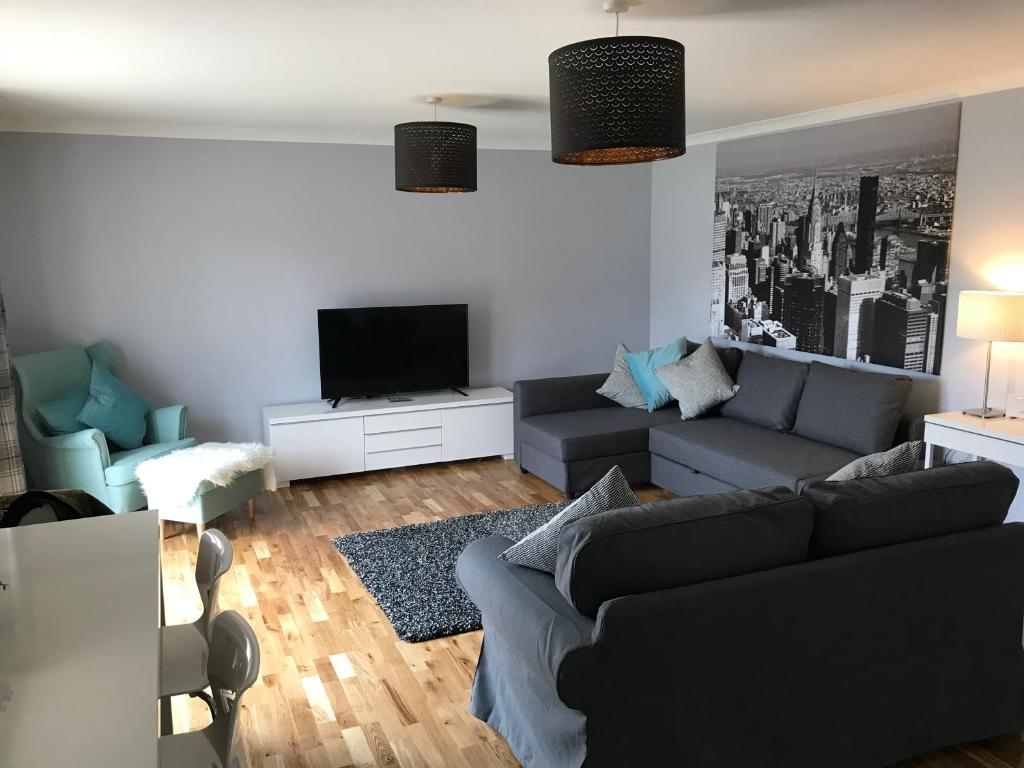 uma sala de estar com um sofá e uma televisão em Flat Five, 212 Eaglesham Road, East Kilbride, Glasgow em East Kilbride