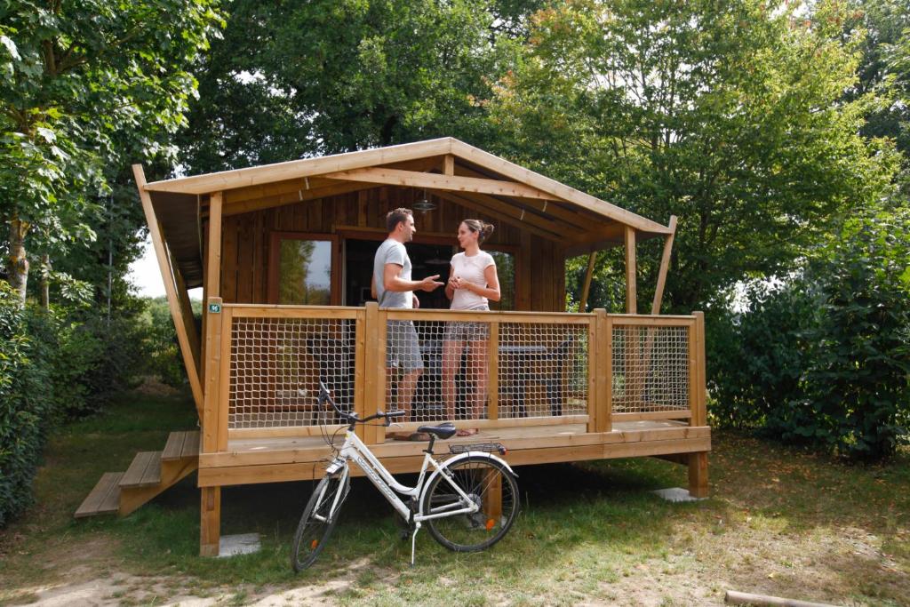 a man and woman standing in a gazebo with a bike at Camping Capfun La Bretèche in Les Épesses