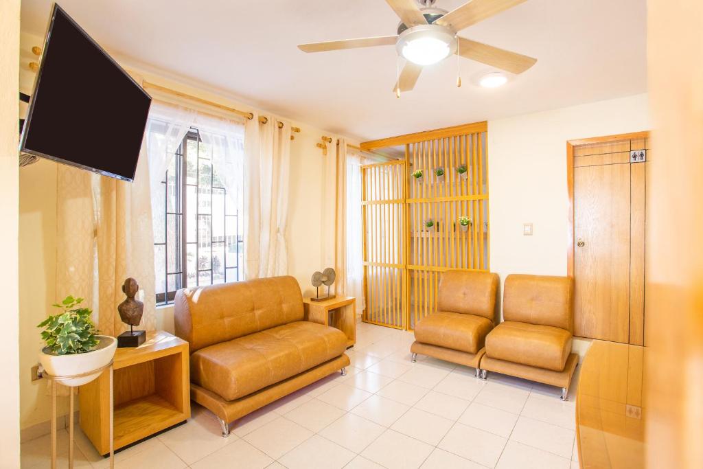 a living room with two chairs and a flat screen tv at La Casa de los Alcatraces in Cancún