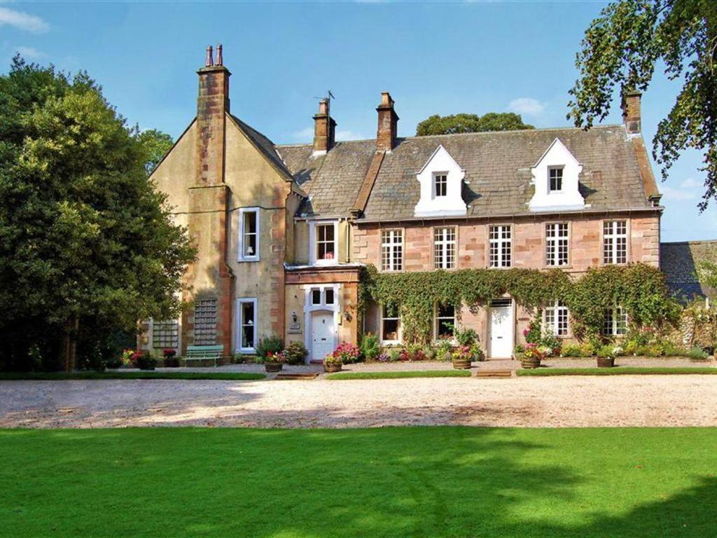 una gran casa de ladrillo con un gran patio en Barton Hall Country House, en Pooley Bridge