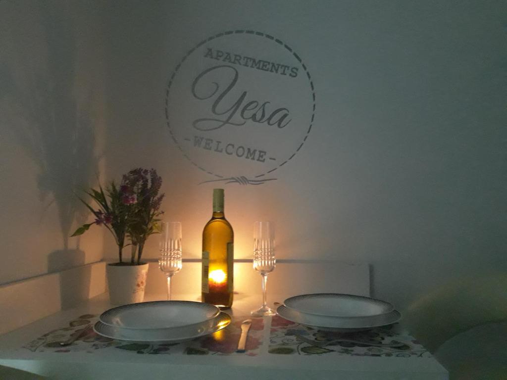 - une table avec deux assiettes et une bouteille de vin dans l'établissement Apartment YESA, à Travnik