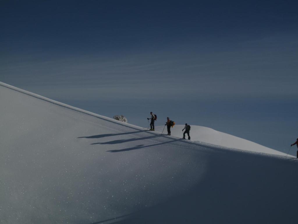 3 persone in piedi sulla cima di un pendio innevato di Rifugio Il Ginepro dell'Etna a Linguaglossa