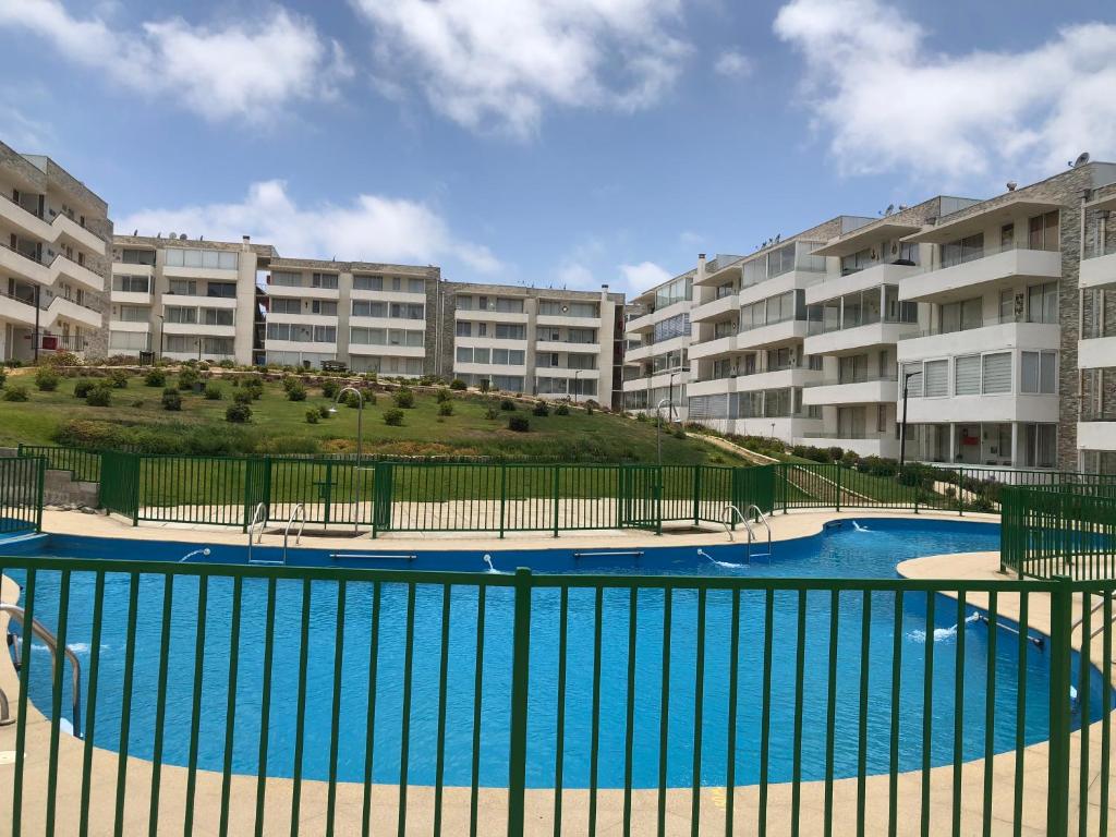 a swimming pool in front of some apartment buildings at Departamento Nuevo in El Tabo