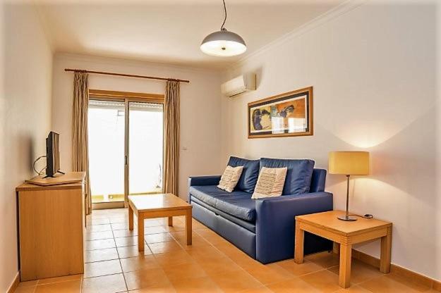 un salon avec un canapé bleu et une télévision dans l'établissement Veleiro Verde, à Monte Gordo