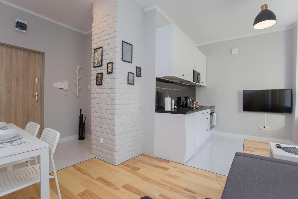 a white living room with a kitchen and a table at CR Apartament przy Katedrze in Białystok