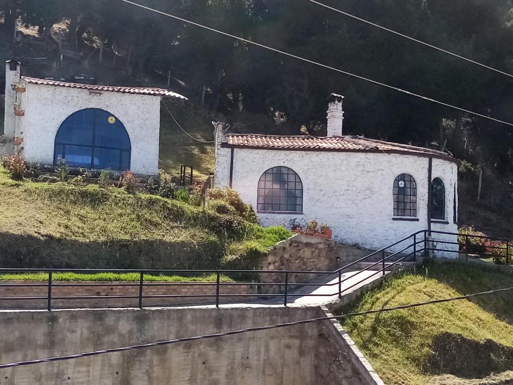 a small white building on a hill with a house at San Rafael de Guaquira II in Aquitania