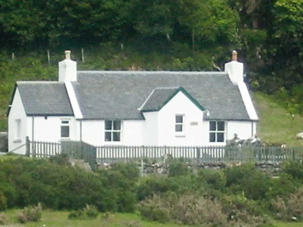 ein weißes Haus mit einem Zaun davor in der Unterkunft Roddy's Cottage in Glenelg