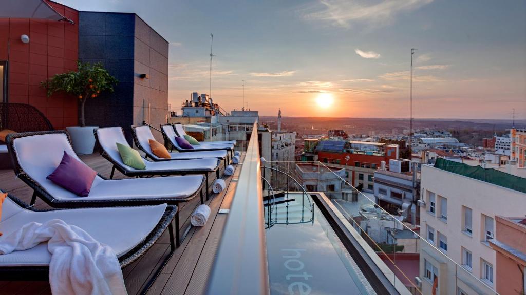 a row of chairs on a balcony with the sunset at Hotel Indigo Madrid - Gran Vía by IHG in Madrid