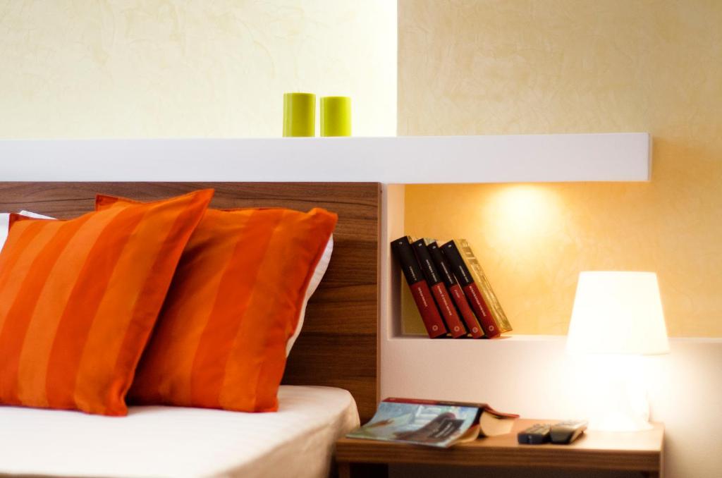 a bed with an orange pillow and a table with a lamp at 6 Apartments in Predeal