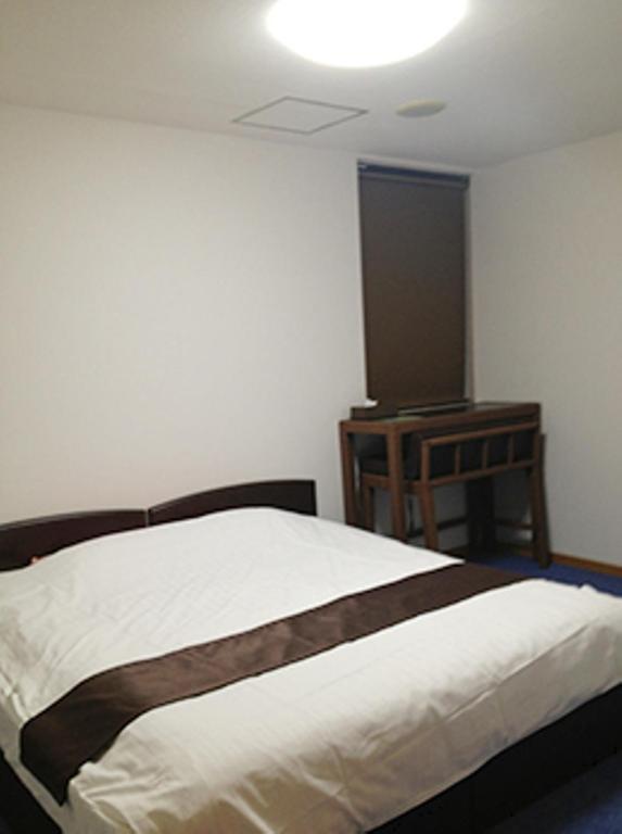 a bedroom with a bed and a table with a light at Sea Queen Kainan in Kainan