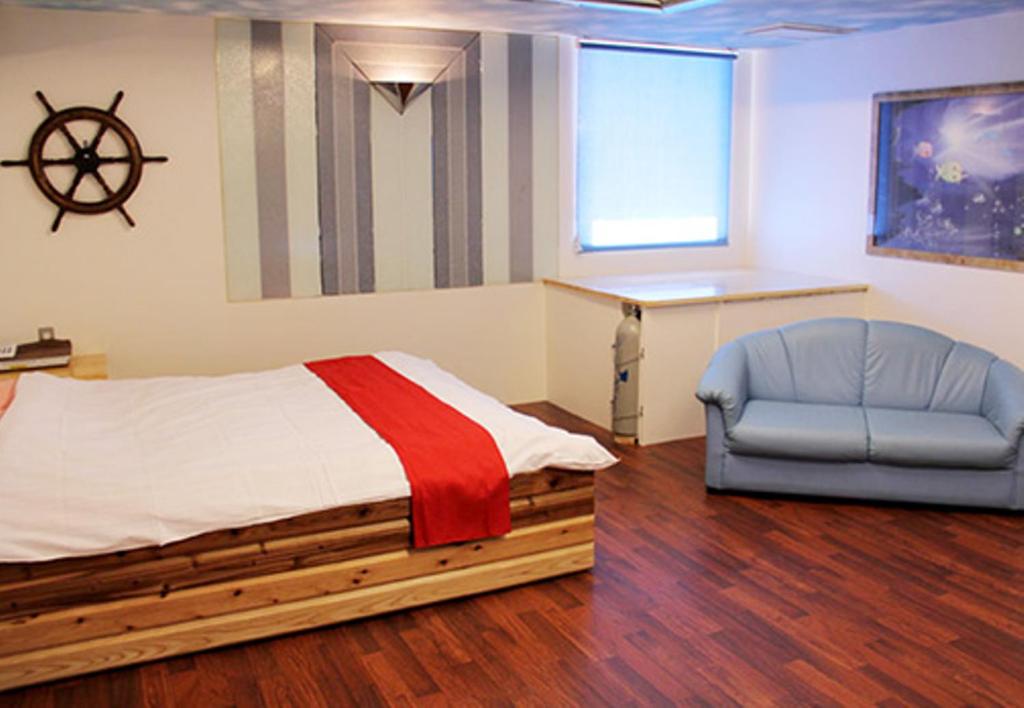 海南市的住宿－海南女王酒店，一间卧室配有一张床和一张蓝色椅子