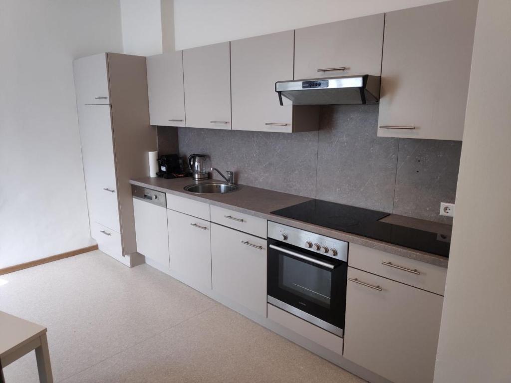 a kitchen with white cabinets and a sink and a stove at Flataid Apartment Reitschulgasse - City Center - Jakominiplatz in Graz