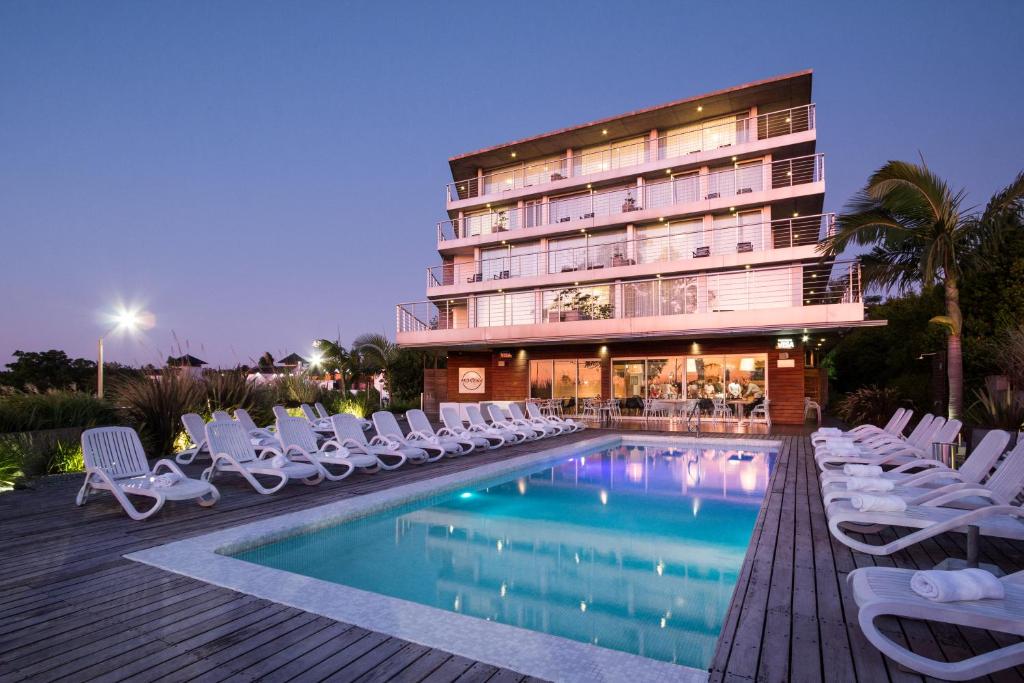 un hotel con piscina, sillas y un edificio en Costa Colonia - Riverside Boutique Hotel, en Colonia del Sacramento