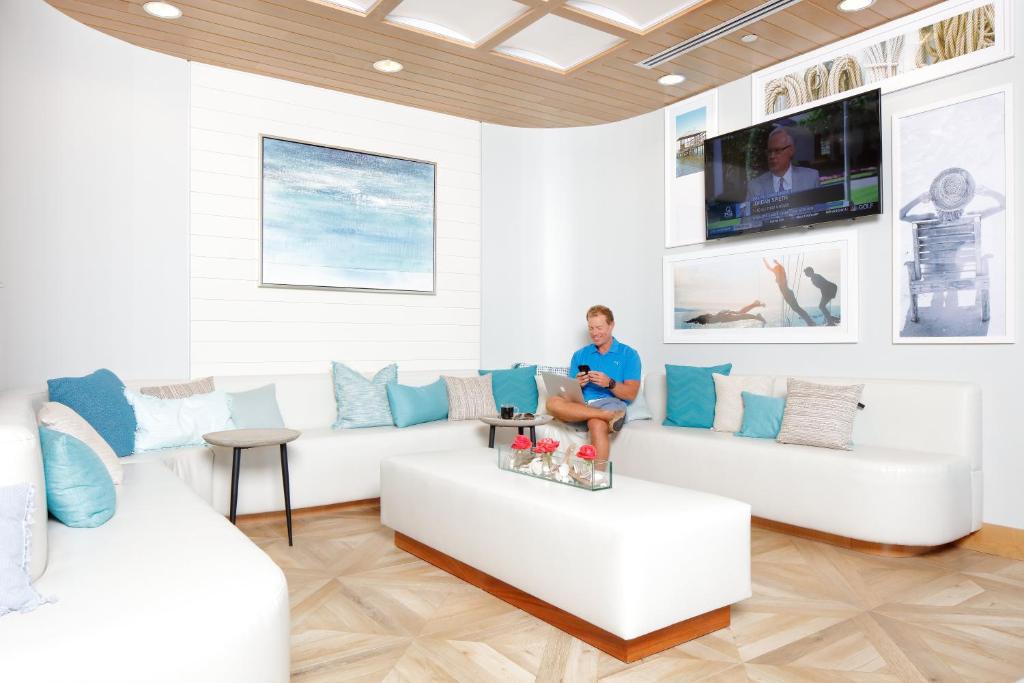 a woman sitting on a couch in a living room at Hotel Indigo Orange Beach - Gulf Shores by IHG in Gulf Shores