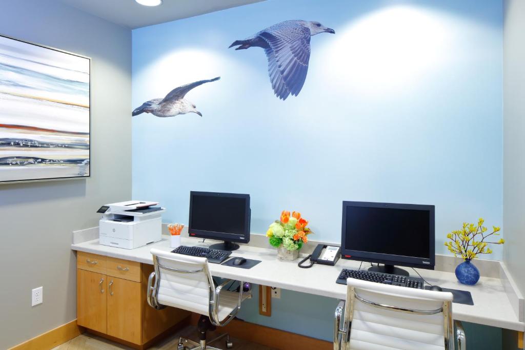 two birds flying over a desk with two computer monitors at Hotel Indigo Orange Beach - Gulf Shores by IHG in Gulf Shores