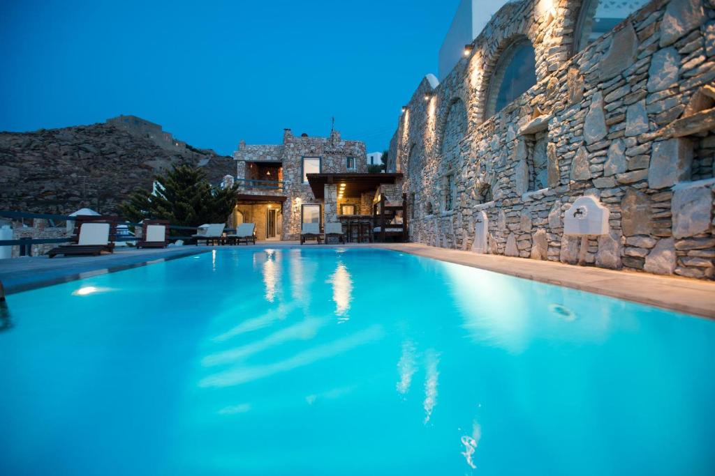 einem großen Pool vor einem Steingebäude in der Unterkunft Villa Omnia in Mykonos Stadt